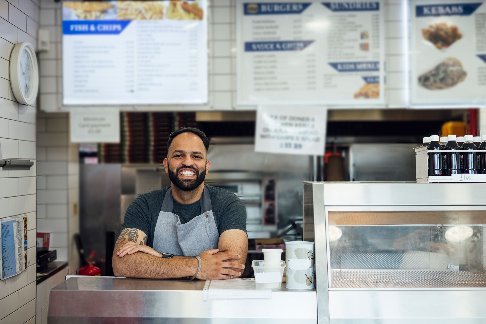 Male restaurant business owner or employee smiling behind counter